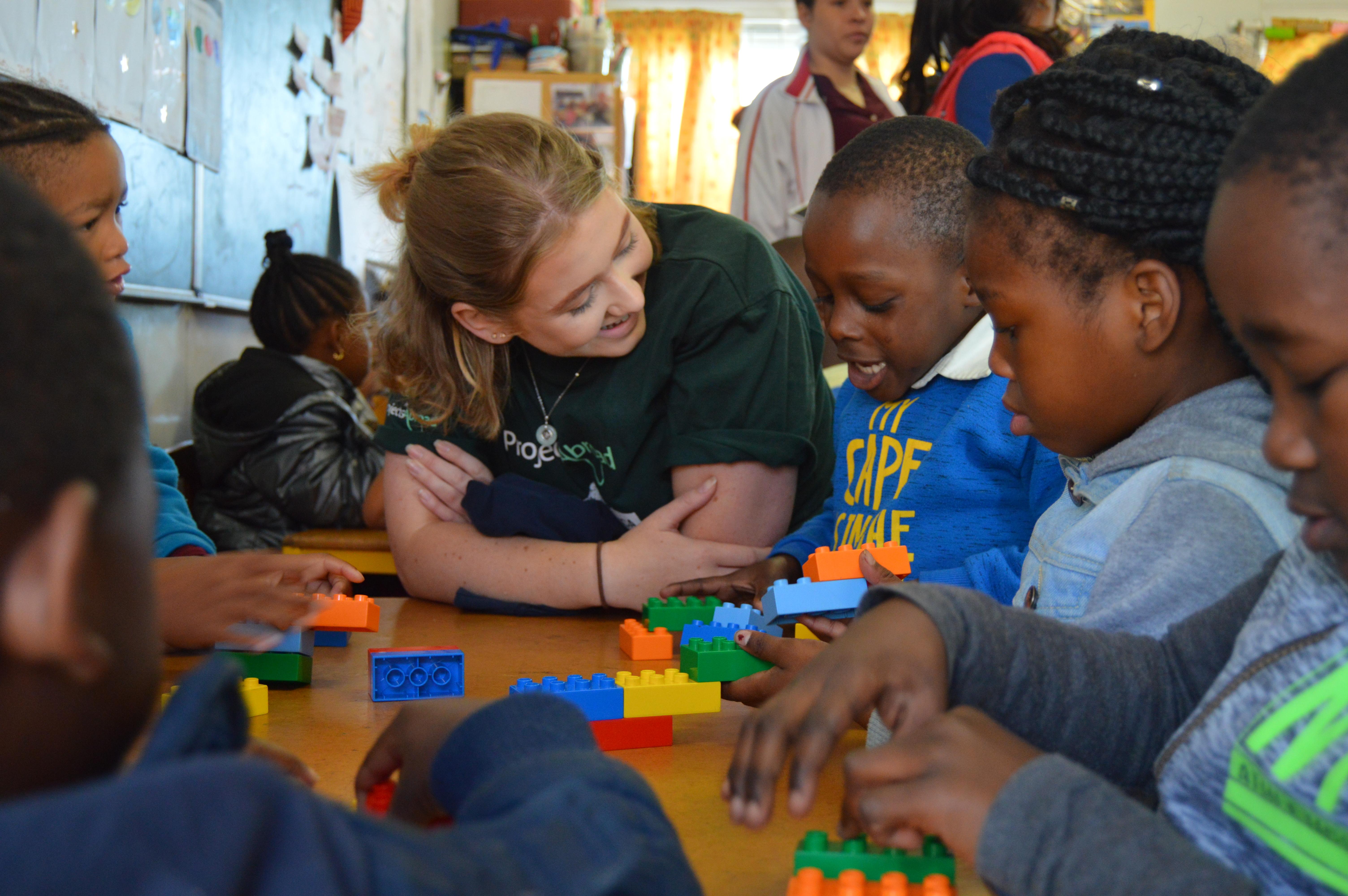 Team Trip volunteer in South Africa sits with a child Volunteer in South Africa sits with children during a lesson